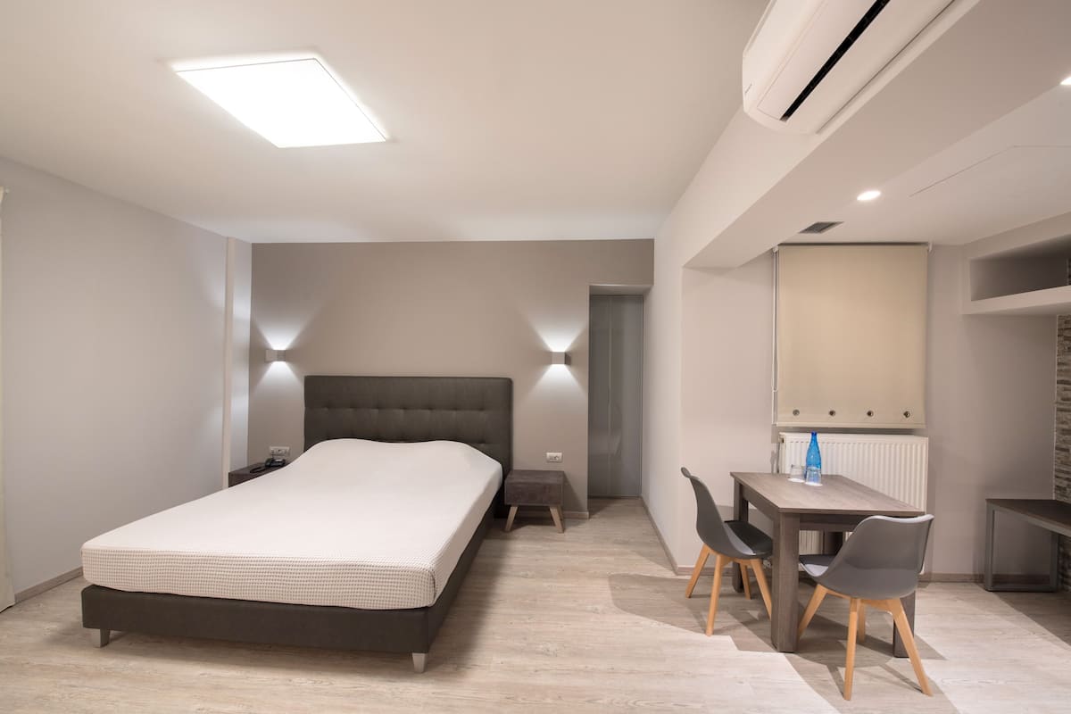 Un dormitorio moderno con una cama grande, mesitas de noche, un escritorio con sillas y un espejo.