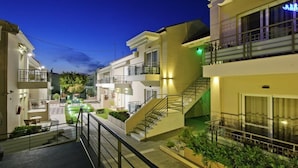 A modern hotel with a central staircase, balconies, and well-lit outdoor areas. - Castello Hotel (Patras)