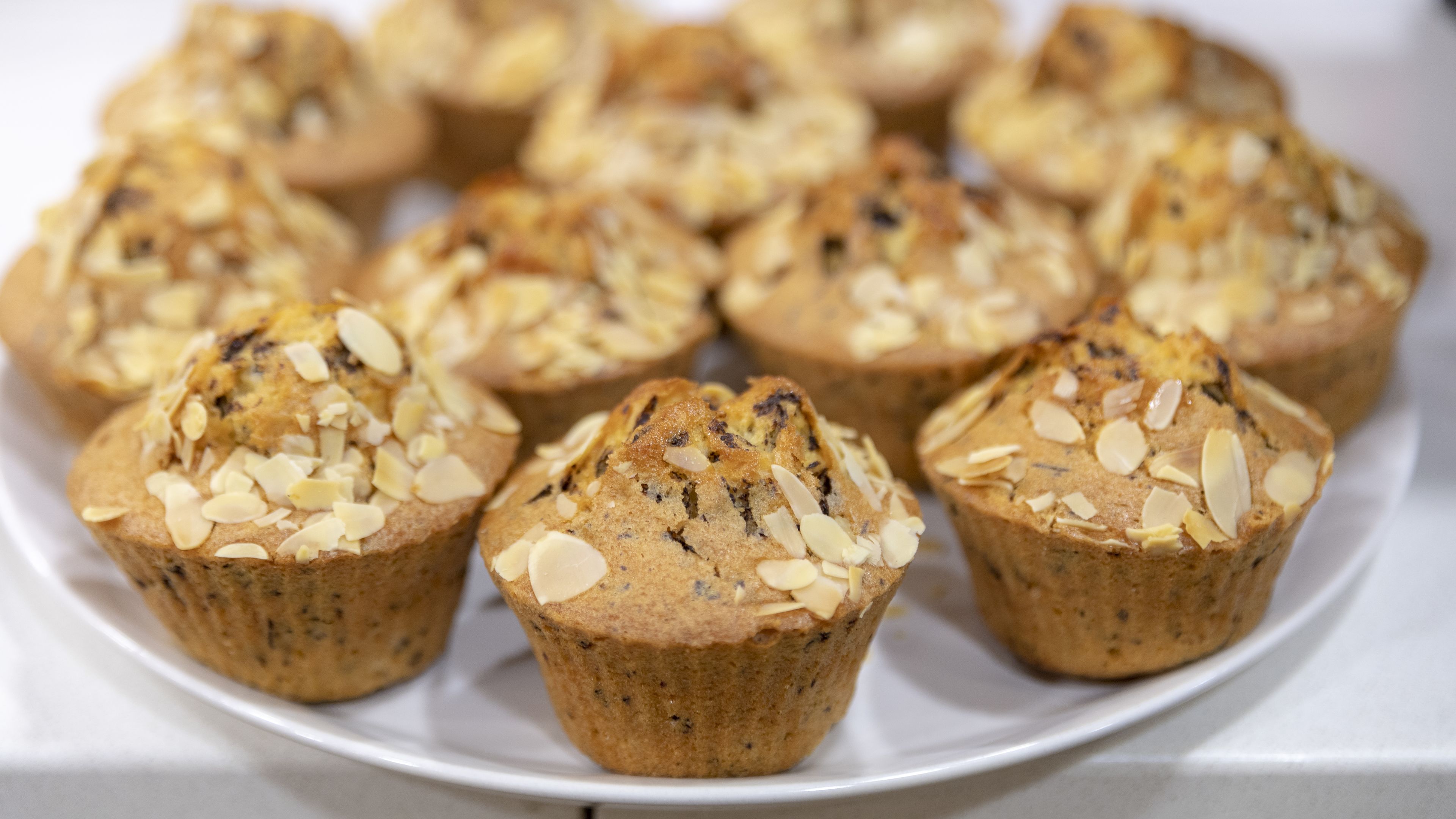 A plate of muffins topped with sliced almonds.