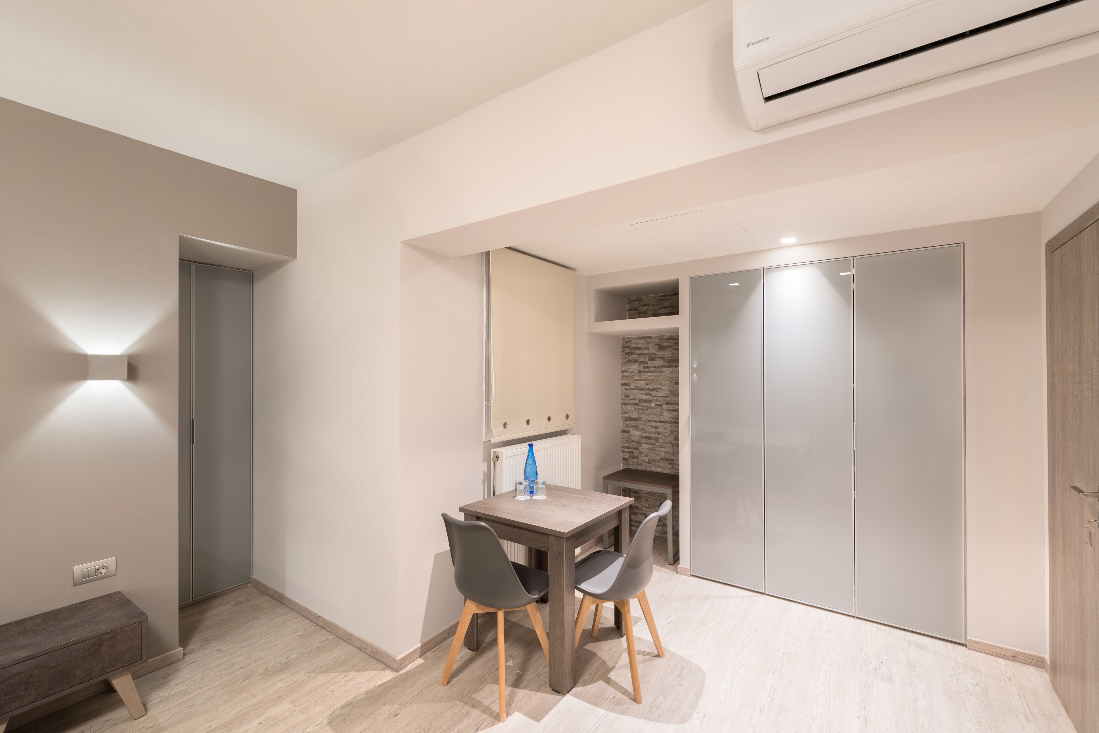 A modern room with a dining table, chairs, a bench, a wardrobe, and a built-in bench along the wall.