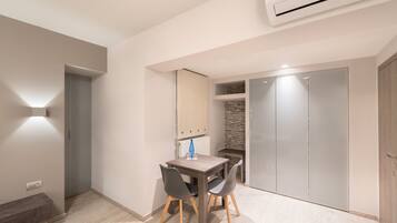 A modern room with a dining table, chairs, a bench, a wardrobe, and a built-in bench along the wall.