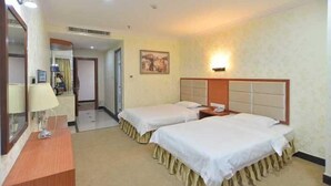 A hotel room with two single beds, a wooden dresser, a mirror, a painting on the wall, and a nightstand with a lamp. - Huaye Hotel (Zhuhai)