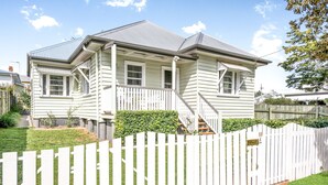 A two-story house with a front porch, a white picket fence, and a well-maintained lawn. - Keeler Cottage (East Toowoomba)
