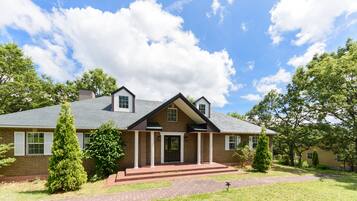 A two-story brick house with a front porch, a chimney, and a well-maintained lawn.