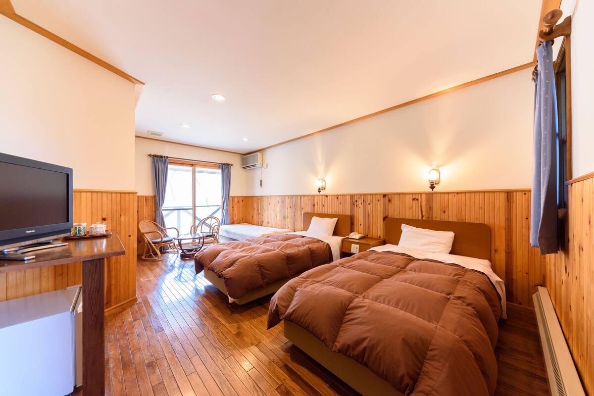 Habitación de hotel con dos camas, televisión, escritorio y silla.