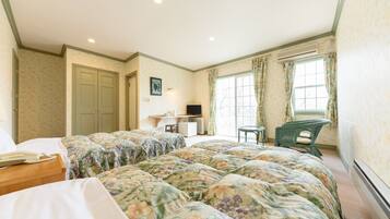 A bedroom with floral bedding, a desk, and a chair.