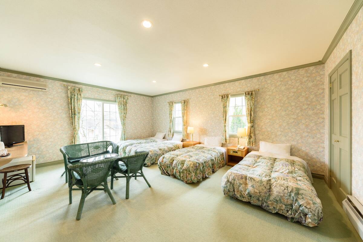 Habitación de hotel con tres camas, un escritorio y una silla.