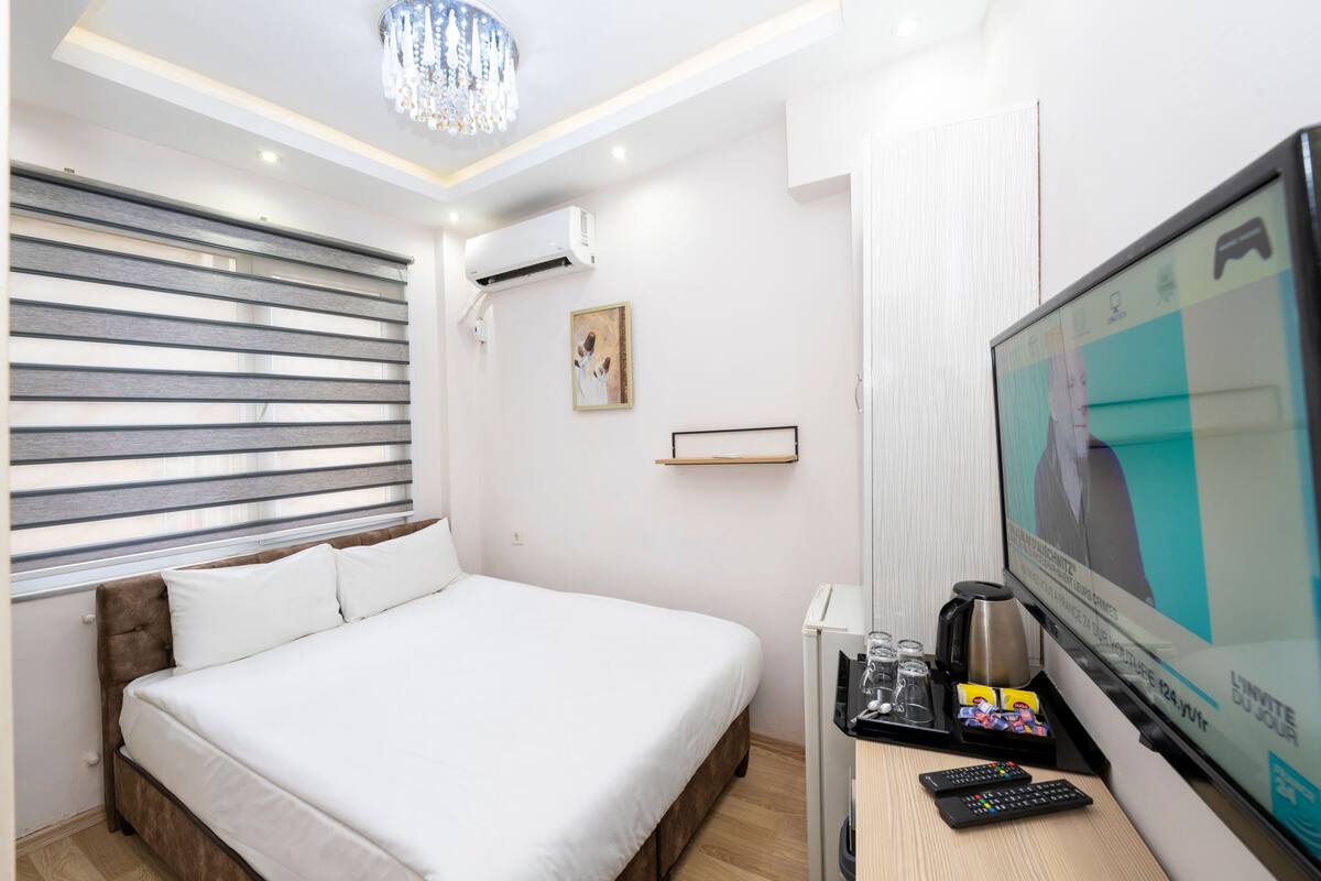 A hotel room with a bed, a TV, a coffee maker, and a remote control.