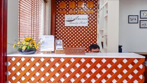 Ein Empfangsschalter mit einem Schild, auf dem 'Ananas Family Hotel' steht, und einem Schild mit der Aufschrift 'RECEPTION'.