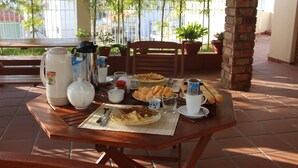 Ein Esstisch mit Kaffeemaschine, Teekanne, Tassen und Tellern mit Speisen.