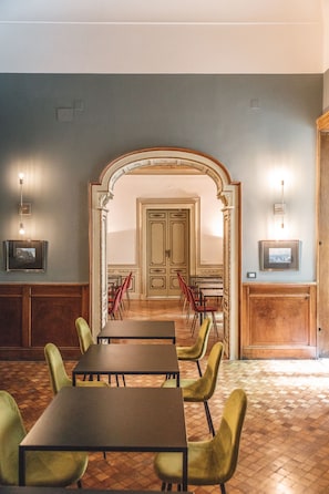Un comedor con mesas y sillas, un arco y cuadros en las paredes.