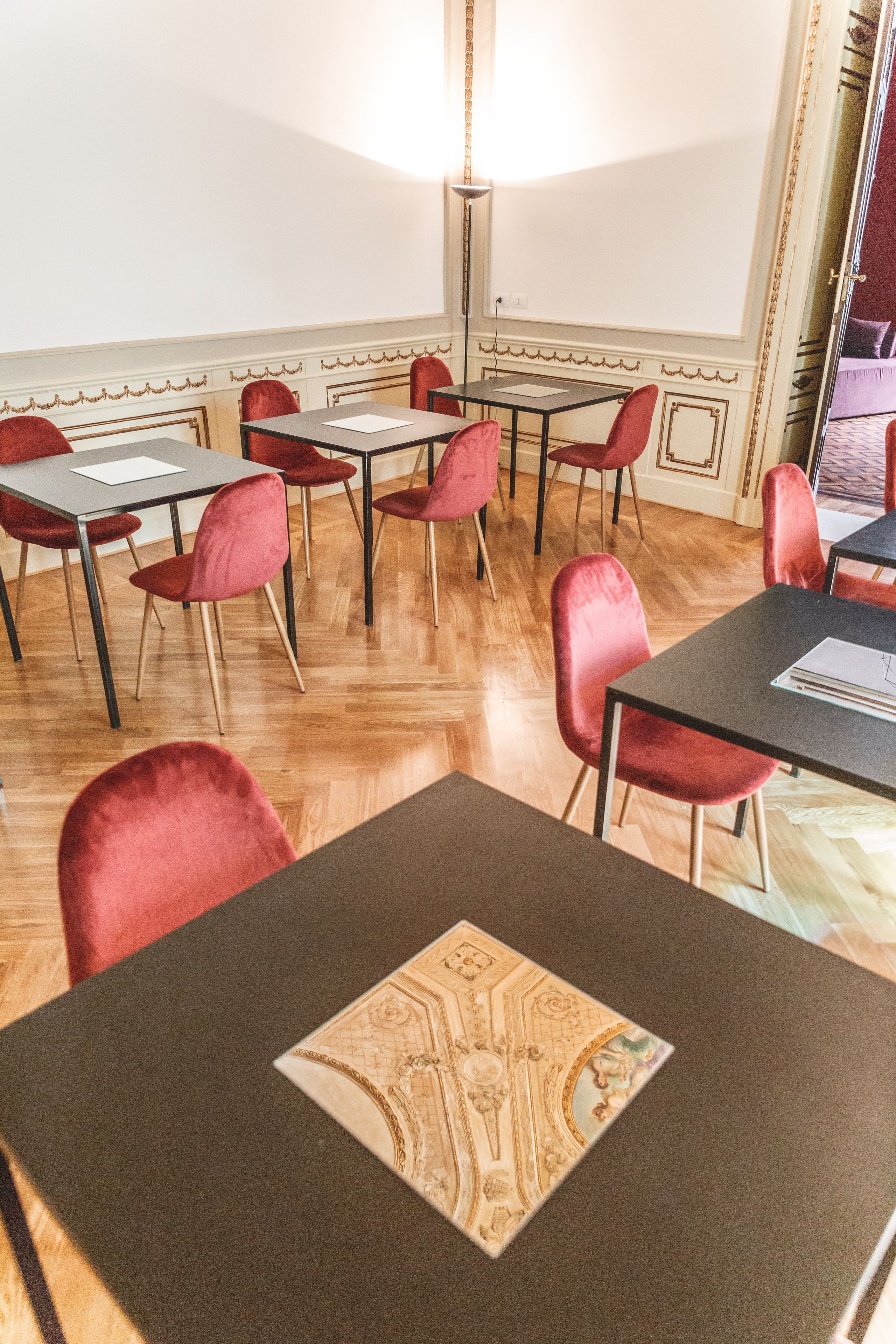 Ein Konferenzraum mit Tischen, Stühlen, einer Kandelaber und einer gemusterten Tischläufer.