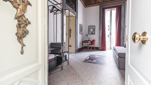 Un couloir avec un plafond orné de motifs, une porte dotée d’une poignée dorée et un rideau rouge.