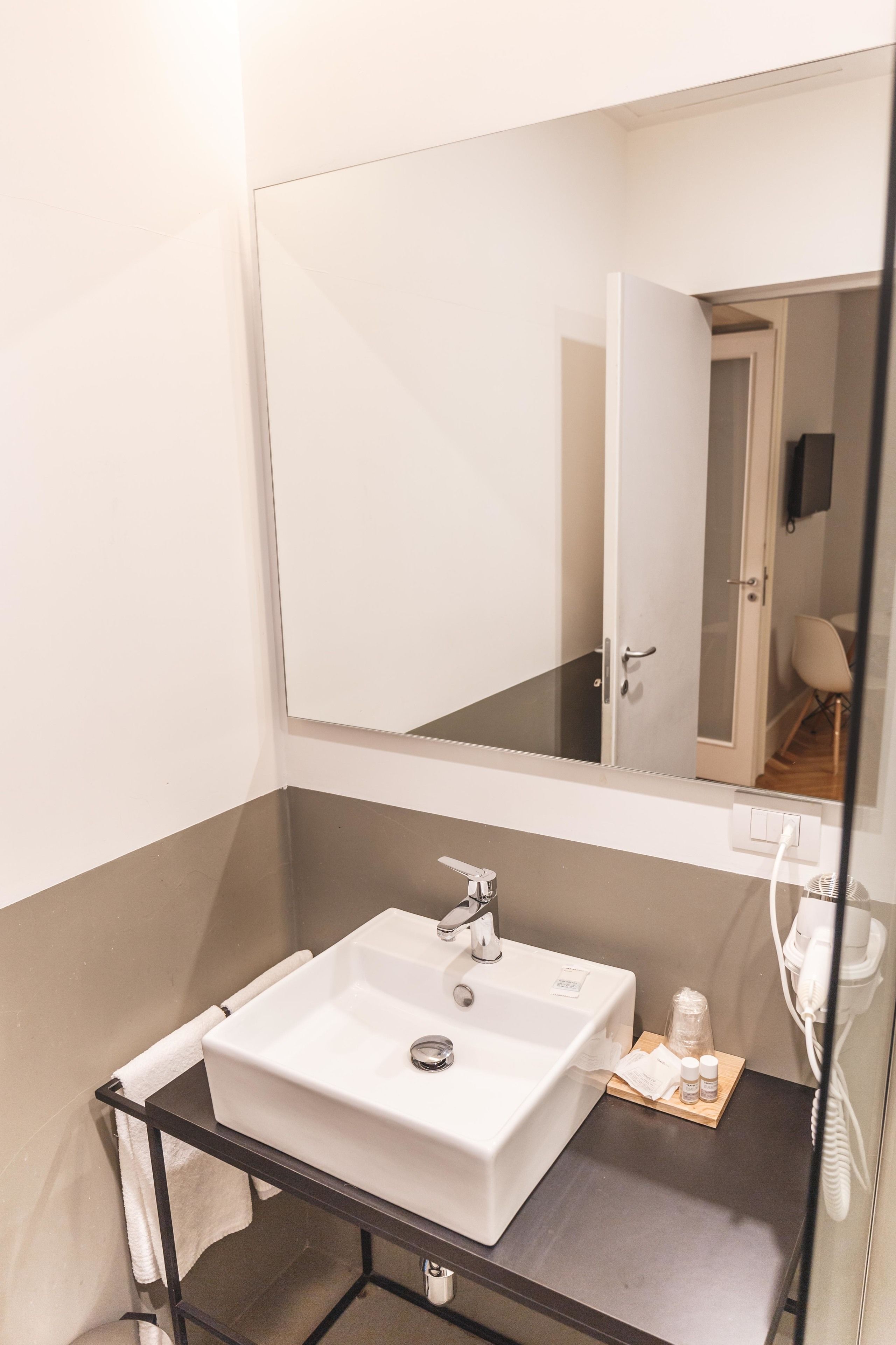 A bathroom with a white sink, a mirror, and a towel rack.