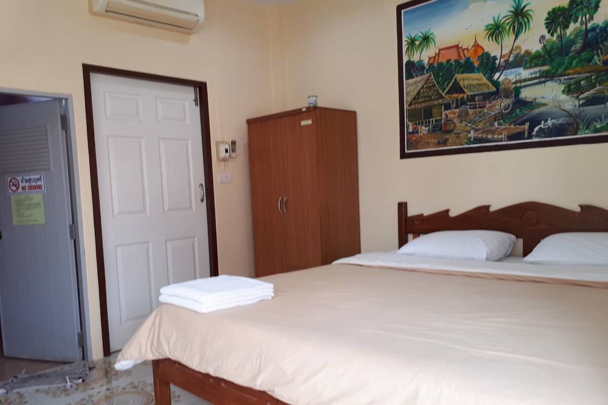 A bedroom with a bed, a wardrobe, a door, and a painting on the wall.