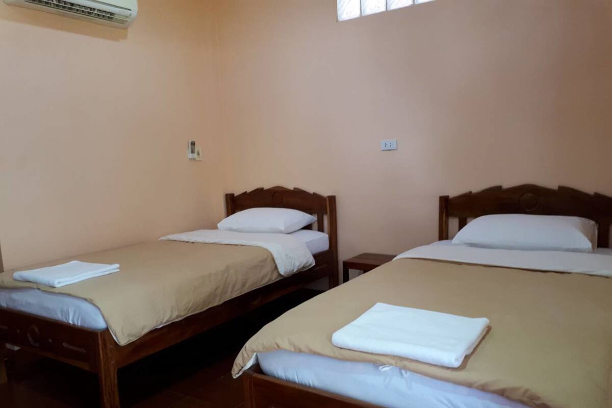 A hotel room with two wooden beds, each with a beige bedspread and white pillows.