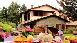 A breakfast table set outdoors with a stone house in the background. - Borgo Caiano Country Inn (Castel San Niccolo)