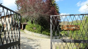 A gated entrance with a 'Welcome' sign, a stone wall, and a pathway leading to a building. - Borgo Caiano Country Inn (Castel San Niccolo)
