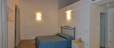 Une chambre à coucher avec un lit, des tables de chevet et deux lampes fixées au mur.