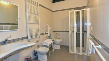 Un baño con lavamanos, inodoro, bidé y cabina de ducha de vidrio.