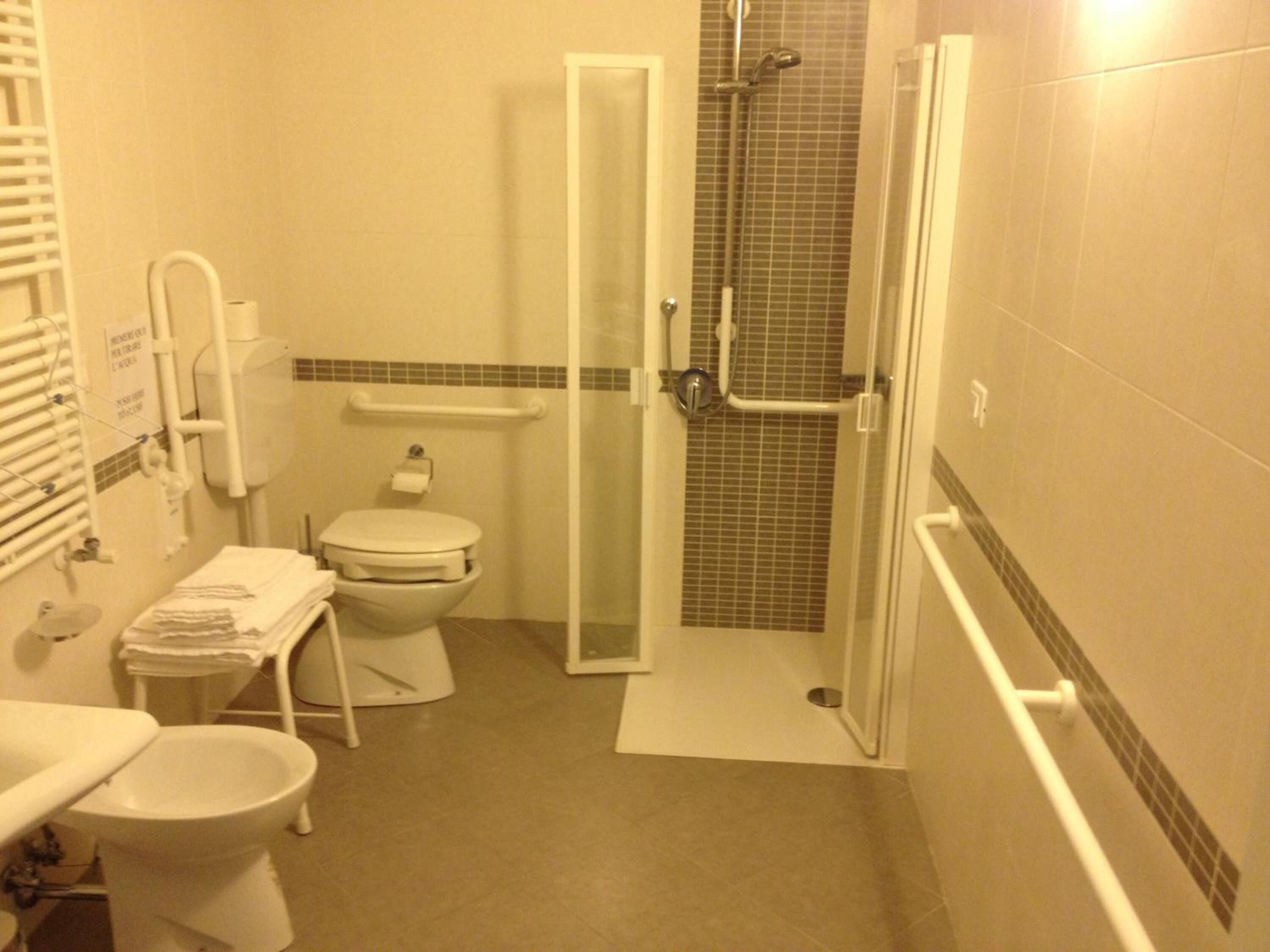 Un baño pequeño con inodoro, lavamanos, ducha y puerta de cristal.