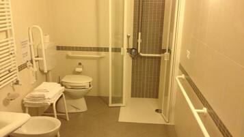 Un baño pequeño con inodoro, lavamanos, ducha y puerta de cristal.