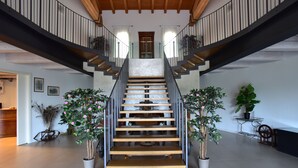 Eine moderne Treppe mit Glastrennungen, Holzstufen und je einer Kübelpflanze an jeder Seite.