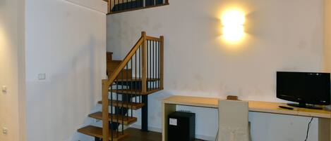 A staircase with wooden railings and a desk with a computer monitor.