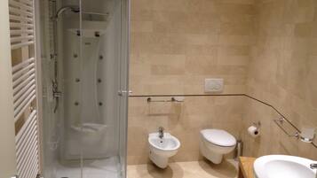 Une salle de bain moderne dotée d’une douche à parois de verre, d’un bidet, de toilettes et d’un lavabo.