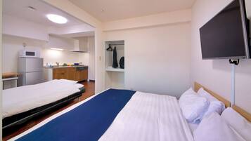 Una habitación de hotel con cama, televisión, microondas y una pequeña kitchenette.