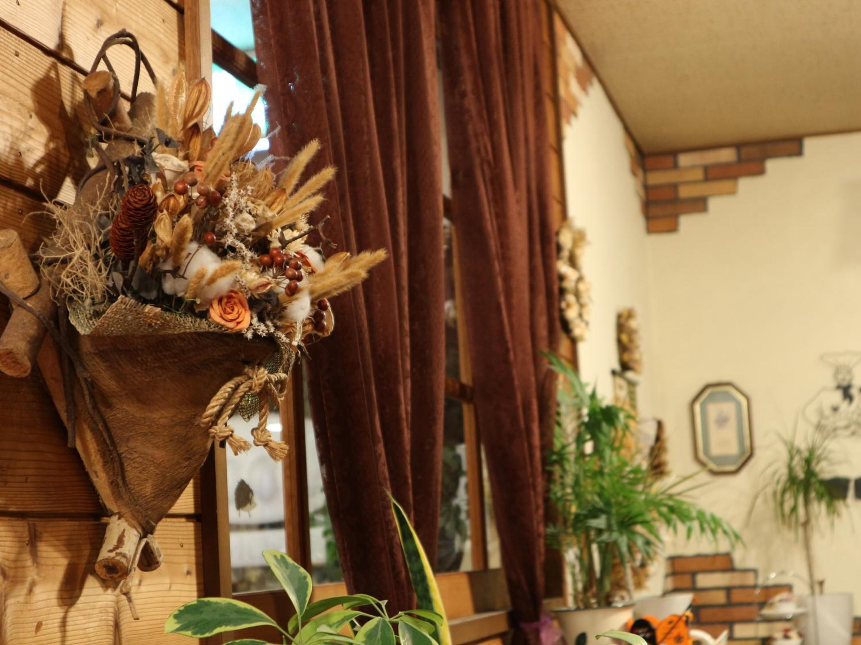 A rustic room with a hanging plant arrangement, wooden walls, and a brick-patterned floor.