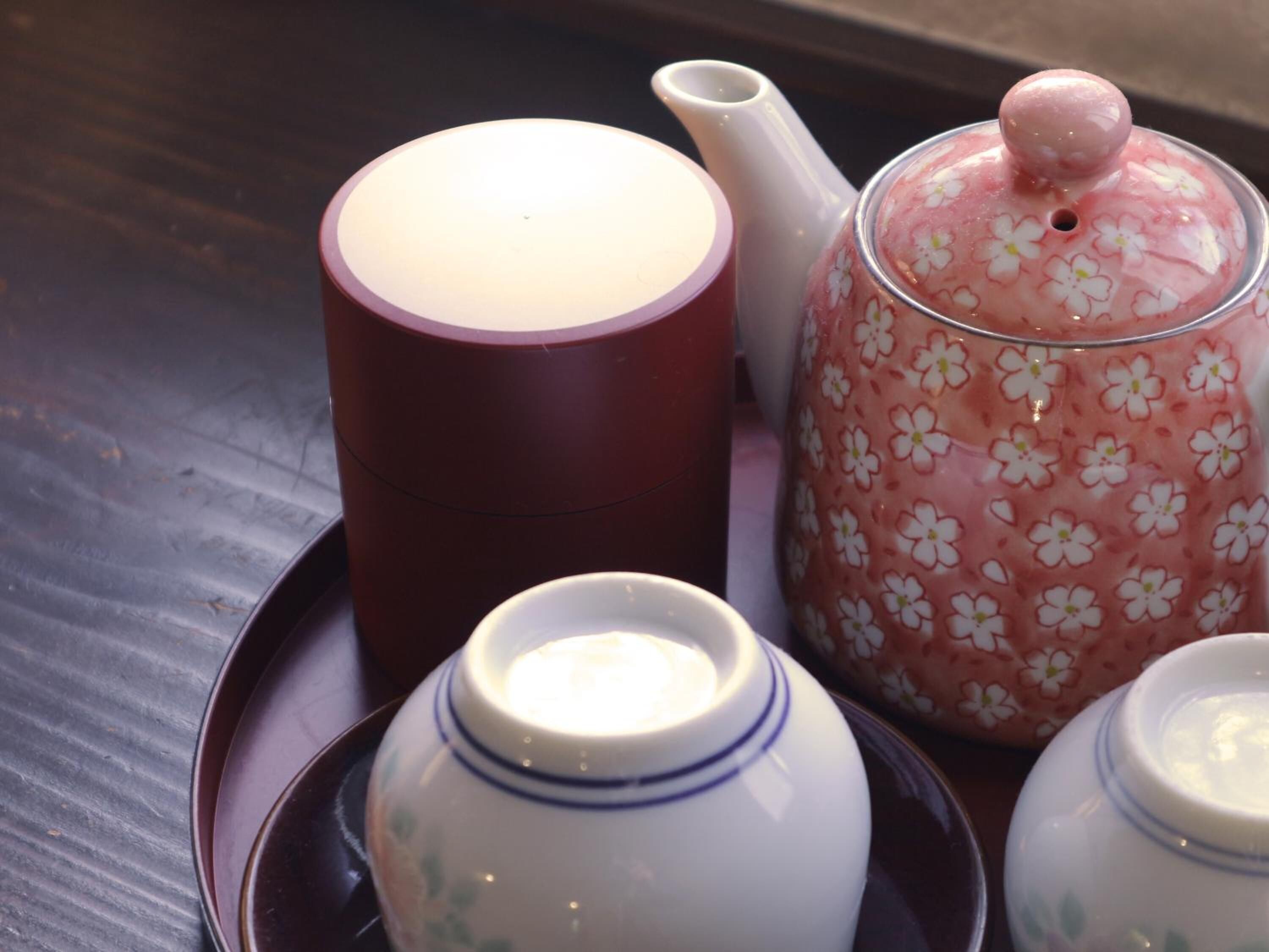 A tea set with a teapot, a cup, and a sugar bowl on a tray.