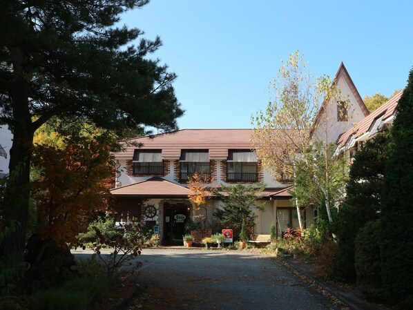 A building with a central entrance, multiple windows, and a surrounding garden.