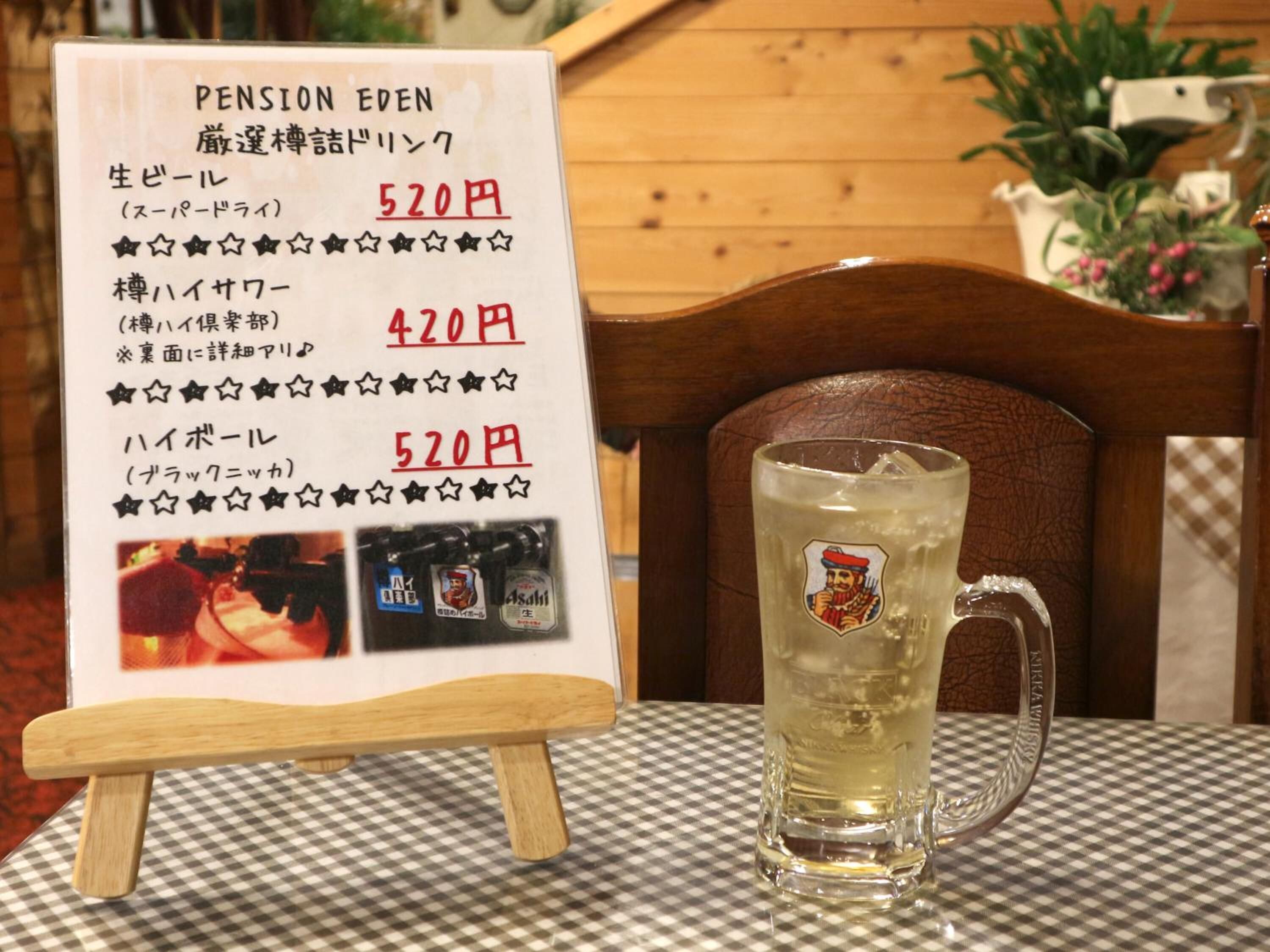 Um quadro de menu com itens e preços em japonês, uma toalha xadrez e uma caneca de vidro com um logotipo sobre uma mesa.
