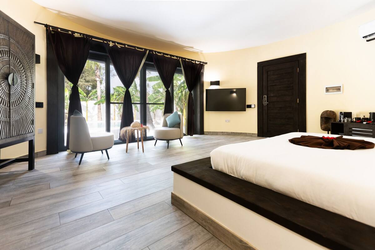 Un dormitorio moderno con una cama grande, televisión, escritorio y vistas al exterior.