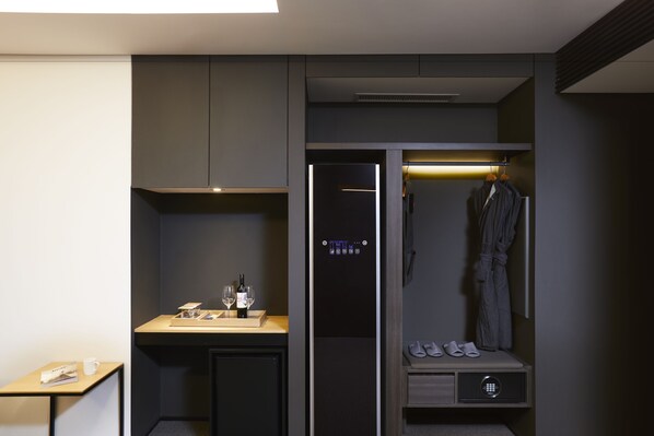 A modern hotel room with a built-in minibar, a robe hanging on the wall, and a shoe storage area. - Glad Mapo (Seoul)