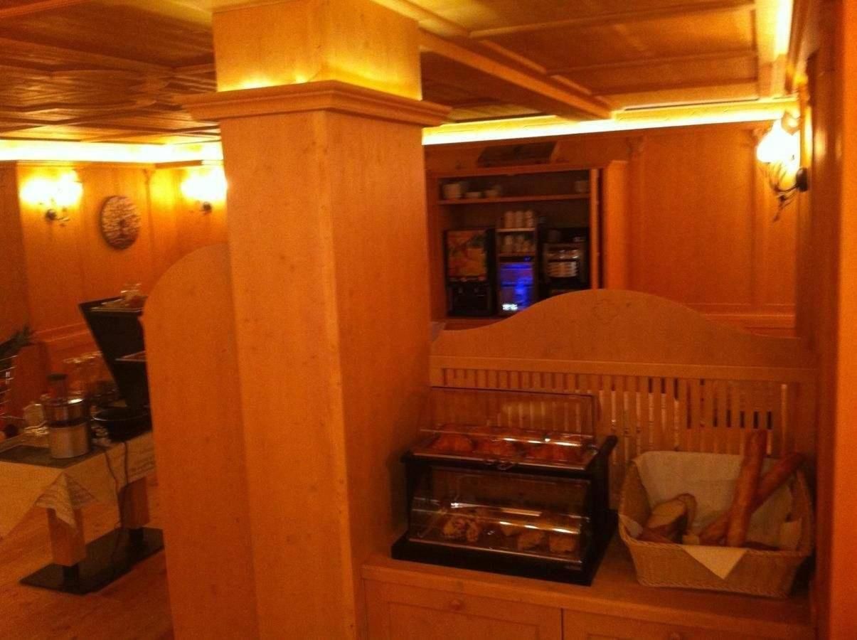 A cozy room with wooden walls, a small kitchenette, and a display case with baked goods.