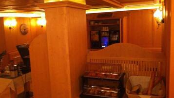A cozy room with wooden walls, a small kitchenette, and a display case with baked goods.