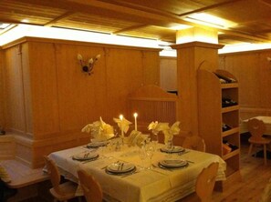 A dining area with a table set for six, featuring white tablecloths, candles, and glassware. - Relais Fior di Bosco (Folgaria)