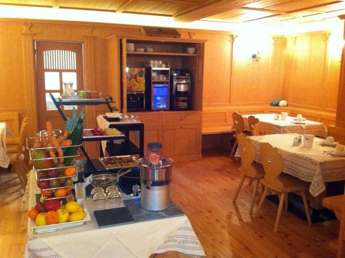 A dining area with a buffet setup, a coffee machine, and a refrigerator in the background.