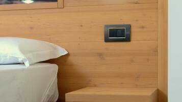 A wooden bedside table with a power outlet and a small shelf.