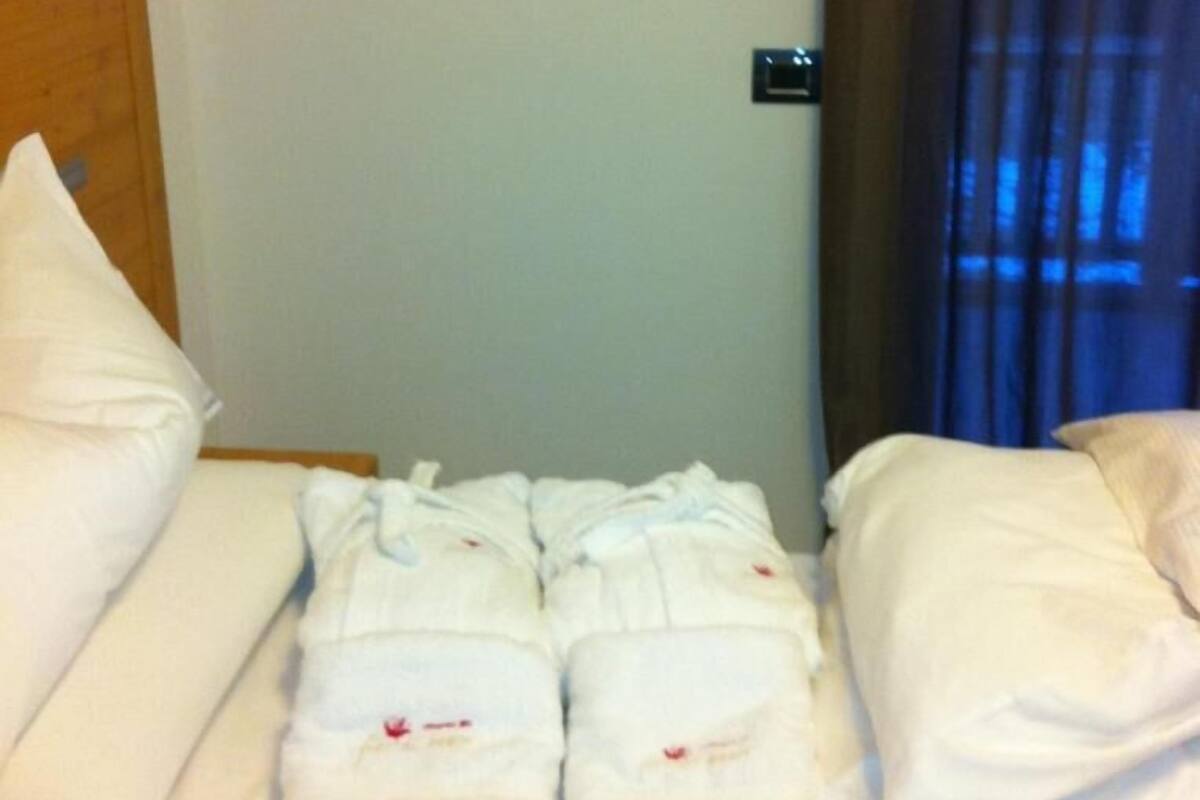 Habitación de hotel con una cama bien hecha, una decoración con forma de corazón en la pared y una ventana con cortinas.