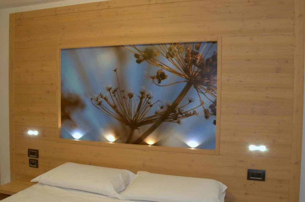 Eine Holzwand mit einem großen gerahmten Bild von Blumen und einem Bett mit weißen Leinen.