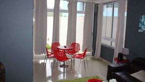 A modern living room with a red dining set, a black sofa, and a red side table. - James East Legon Piece (Accra)