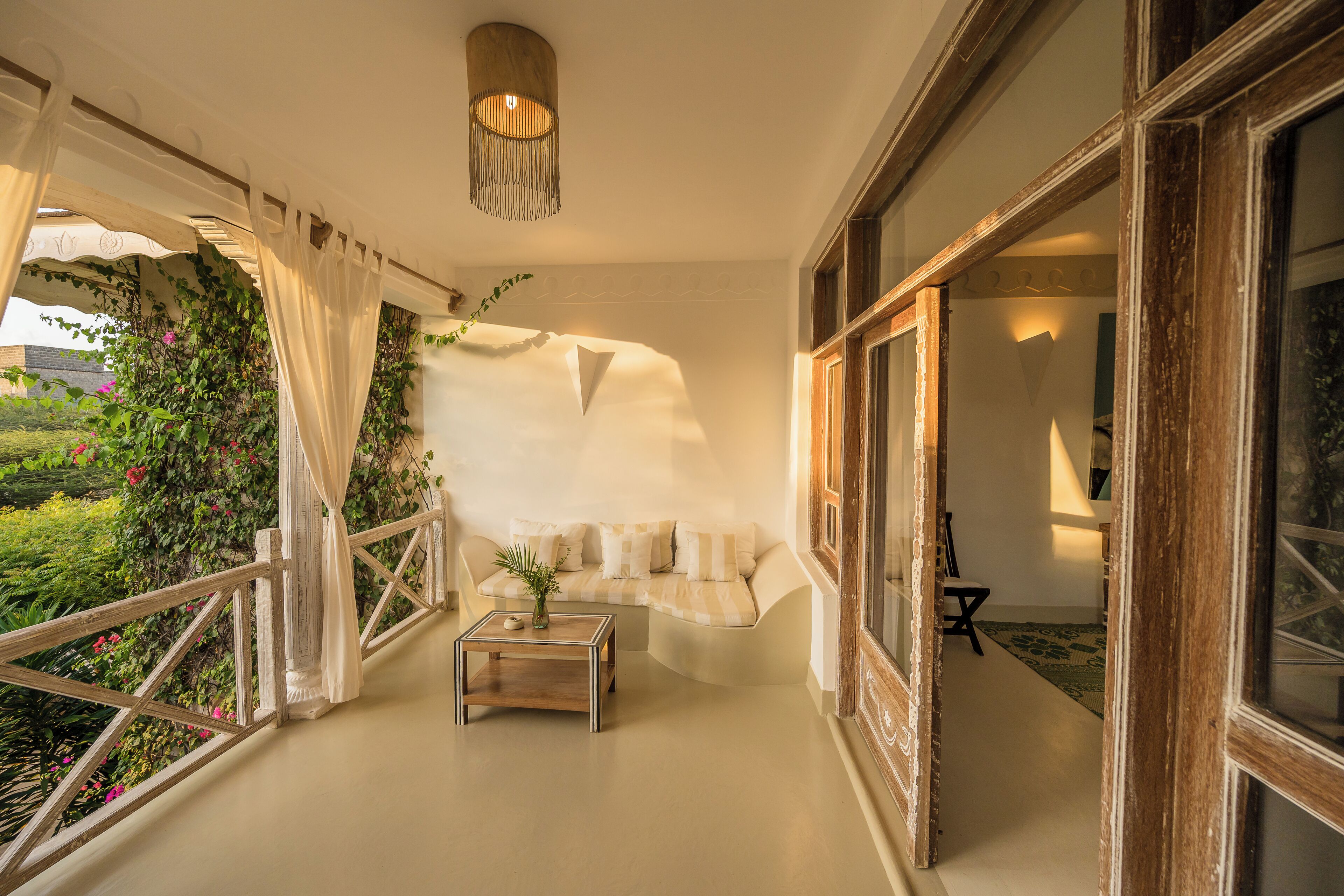 A room with a sofa, a small table, and a hanging plant.