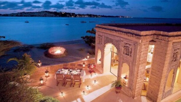 Un espace de restauration situé en bord de mer, avec un foyer, des sièges en plein air et une vue sur la mer.