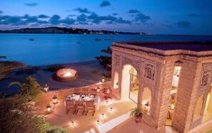 A beachfront dining area with a fire pit, outdoor seating, and a view of the sea. - The Majlis Hotel (Manda Island)