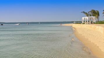 Una playa con agua cristalina, un quiosco blanco y palmeras.