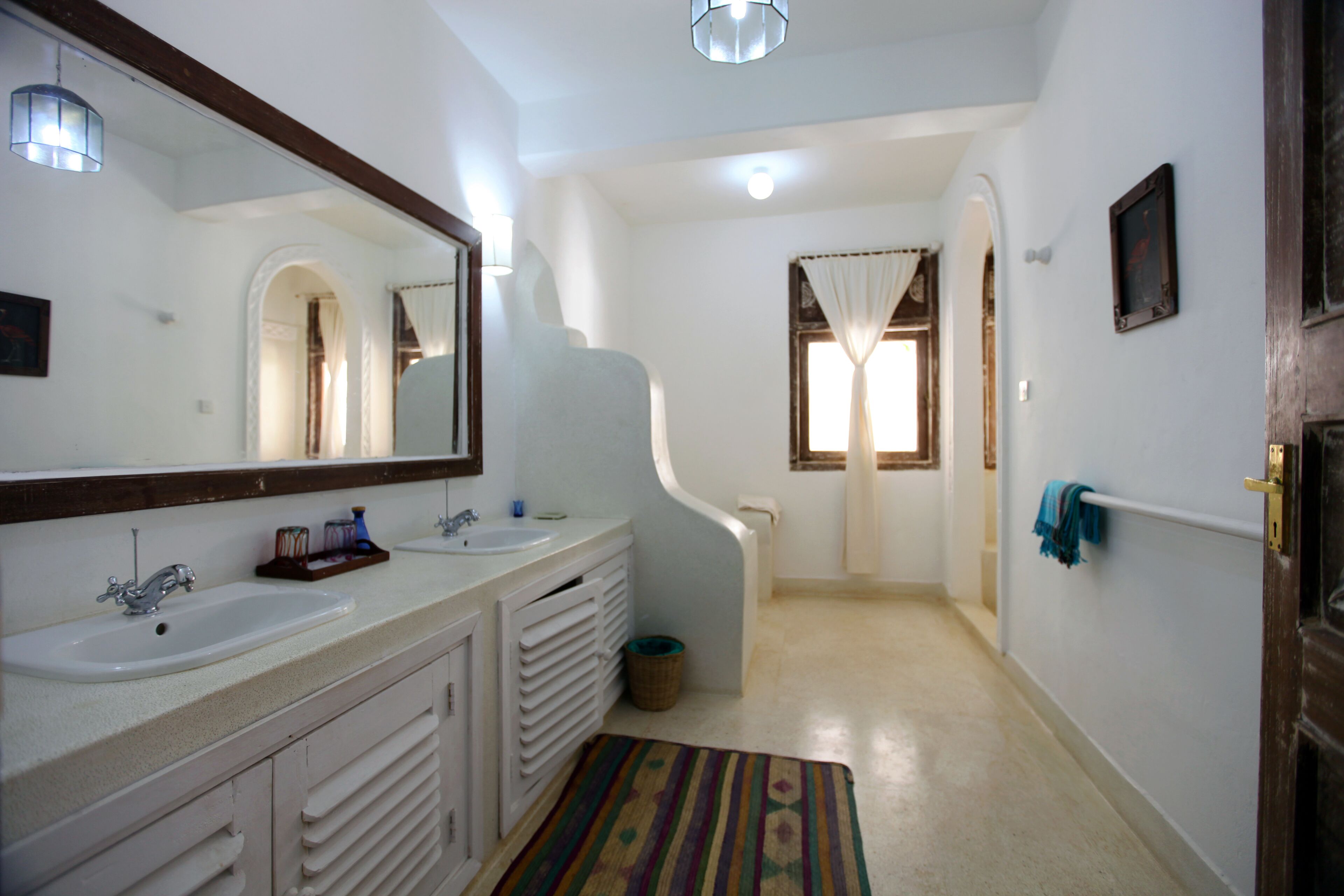 A bathroom with two sinks, a large mirror, and a shower area.