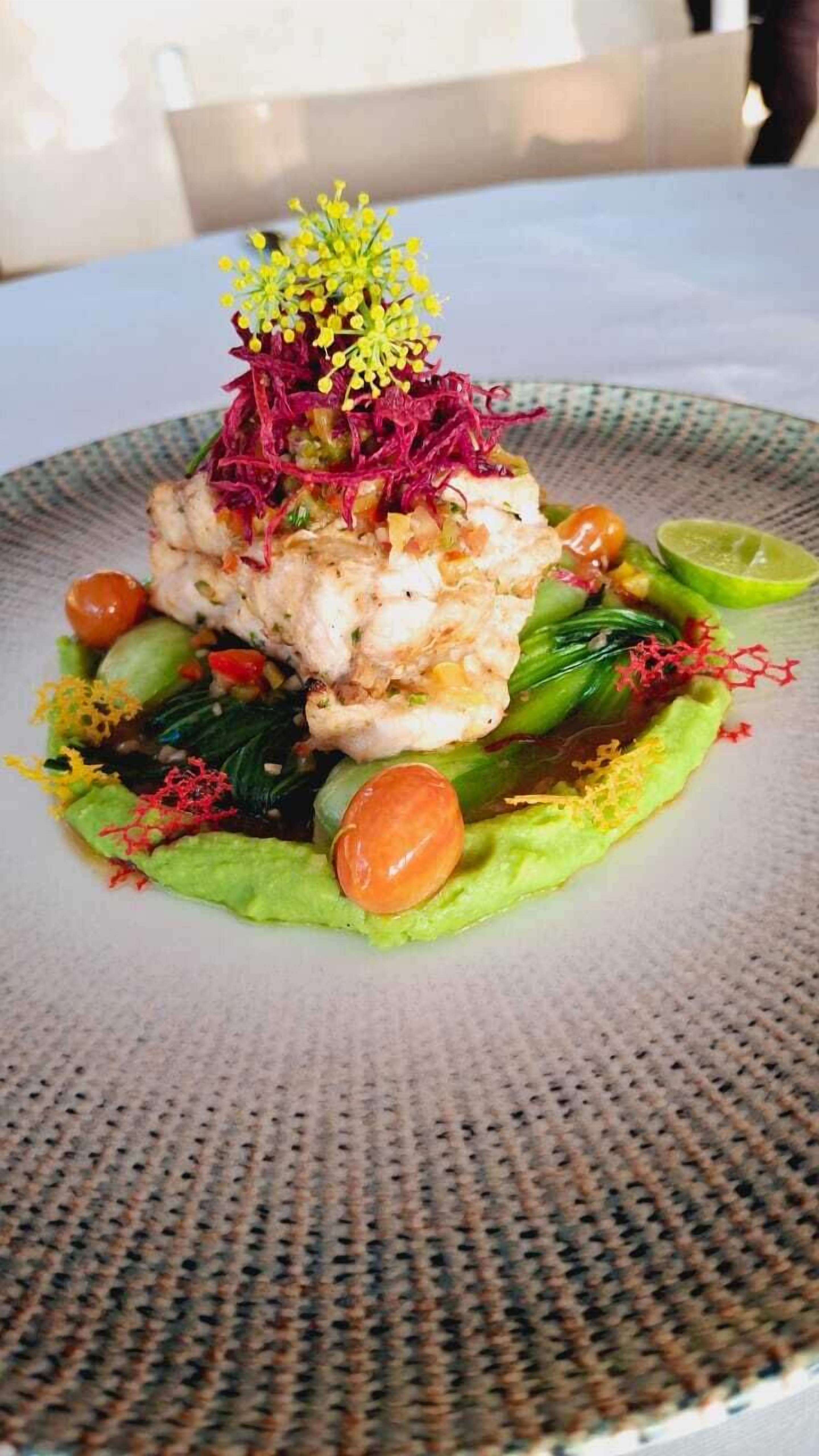 Een bord eten met diverse groenten en een decoratieve garnering.